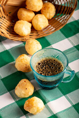 Brazilian cheese bread with coffee, delicious Brazilian cheese bread with a cup of coffee and accessories on a rustic table with a green and white checkered tablecloth, selective focus.