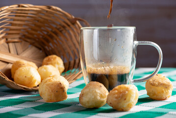 Brazilian cheese bread with coffee, delicious Brazilian cheese bread with a cup of coffee and accessories on a rustic table with a green and white checkered tablecloth, selective focus.