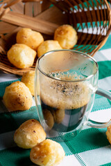 Brazilian cheese bread with coffee, delicious Brazilian cheese bread with a cup of coffee and accessories on a rustic table with a green and white checkered tablecloth, selective focus.