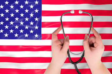 Medical stethoscope in hands (close-up) against the background of the US flag. American healthcare system concept