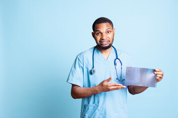 Male nurse analyzing radiology x ray scan to provide patient with diagnosis during medical exam, studio background. General practitioner doing body examination, scanning radiography.