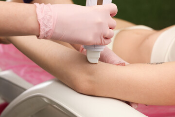 Professional cosmetologist waxing client's arm with roller in beauty salon, closeup