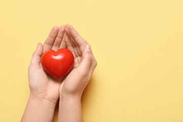 Female hands with red heart on yellow background