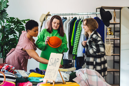 Girls having fun at home swap party. Garage sale, second hand, trying used clothes, exchanging jeans, dresses, accessories . Sustainable fashion, conscious consumption, circular economy concept