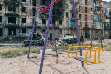 An empty children's playground next to a residential building destroyed by rocket fire. War in Ukraine