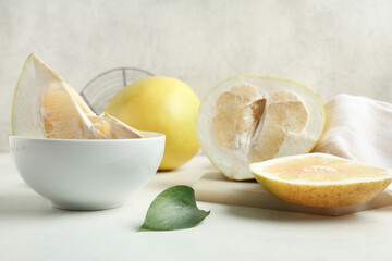 Bowl and board of cut fresh pomelo fruit on white background