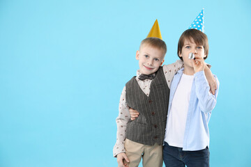 Children in conical paper hats with blower on light blue background, space for text. Birthday...