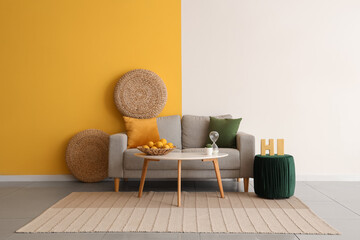 Trendy interior of beautiful living room with comfortable sofa, table, carpet and pouf