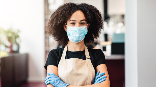 Safe beauty occupation. African american girl hairdresser in protective mask posing at salon, free space