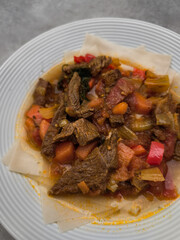 Delicious beef stew with carrots, celery, tomatoes and spices, served on injera, a traditional ethiopian flatbread