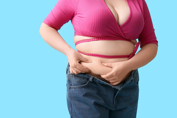 Overweight woman in tight clothes on blue background. Diet concept