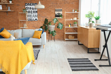 Interior of modern living room with grey sofa, houseplants and wooden cabinet