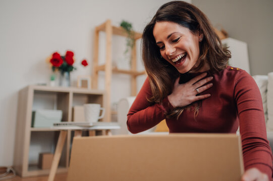 Happy woman opening a surprise package at home