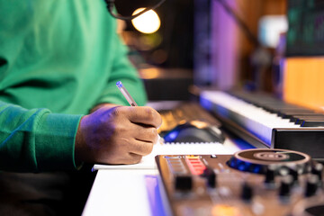 Songwriter taking notes on paper to compose a new soundtrack, making rhymes and mixing musical...