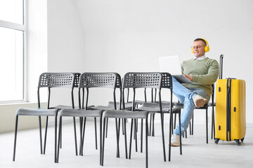 Male tourist in headphones using laptop at airport