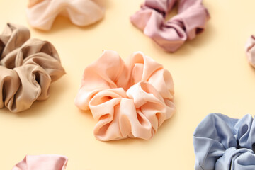 Trendy silk scrunchies on light yellow background