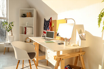 Interior of light office with workplace, shelf unit and USA flags