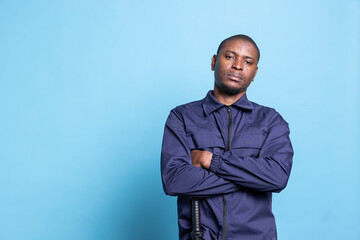 Portrait of confident security agent posing with arms crossed in studio, wearing his safeguarding...