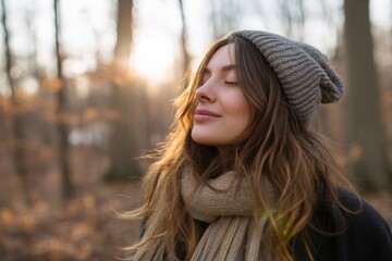 Fototapeta premium Young woman enjoying fresh air in autumn forest with closed eyes