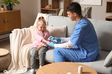 Male pediatrician measuring temperature of little girl with infrared thermometer at home