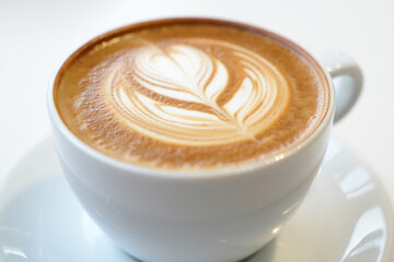 Hot Cappuccino with Foam Art in White Cup and Saucer
