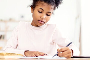 Black Teen Girl Writing Doing Homework Learning Sitting At Table At Home. Selective Focus