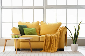 Interior of stylish living room with yellow sofa, coffee table, houseplant and window