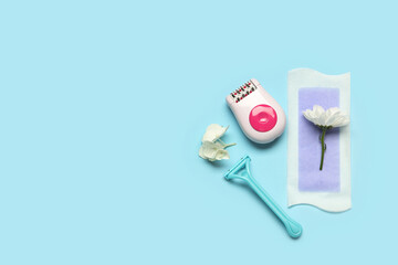 Modern epilator with wax strip, razor and flowers on blue background