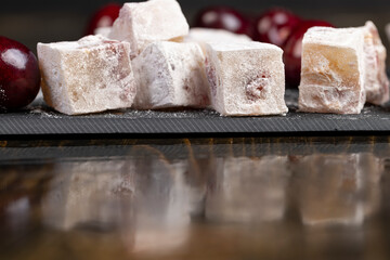 cubes of sweet Turkish delight with the addition of dried red berries, reflection on the table