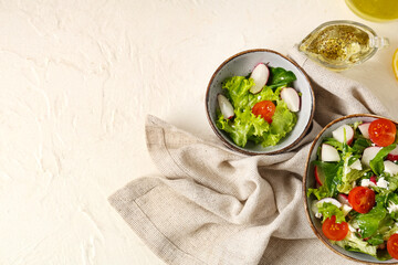 Bowls of salad and oil on light background