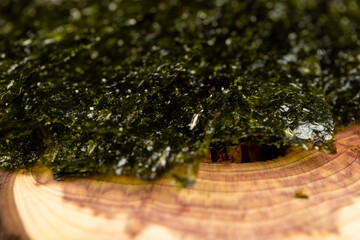 natural green algae that are used to prepare Japanese dishes close up, algae on a larch board