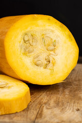 Slice yellow pumpkin or zucchini, slicing ripe zucchini on a black cooking table