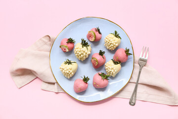 Plate with chocolate covered strawberries on pink background