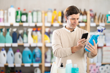 Checking expiration date of spray glass cleaner for windows - male shopper scans QR code on label...