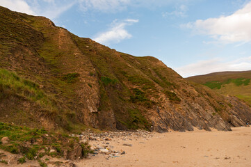 A rocky cliff with a beach in the background