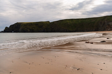 A beach with a rocky cliff in the background