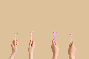 Female hands with razors on beige background