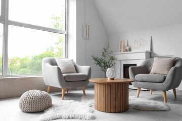 Interior of light living room with paintings, fireplace and armchairs