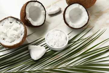 Palm leaf and bowl with natural coconut oil on marble background, closeup