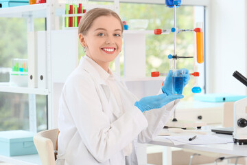 Female chemist with flask at table in laboratory