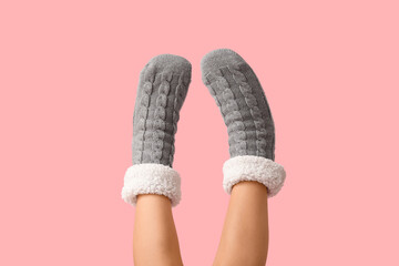 Legs of young woman in grey warm socks on pink background