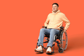 Young man in wheelchair on orange background