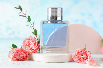 Decorative podiums with bottle of perfume and beautiful pink roses on light blue background