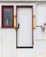 Cabin door and window of old rusty boat.