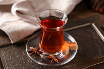 Tray with glass of Turkish tea, anise stars and sugar cubes, closeup