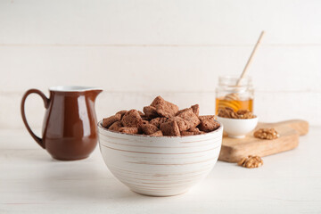 Bowl with chocolate corn pillows on white background