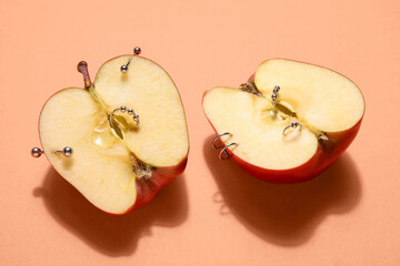 Halves of apple with piercing on orange background