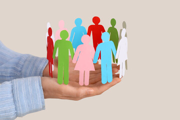 Female hands with colorful paper human figures on light background, closeup. Diversity and...