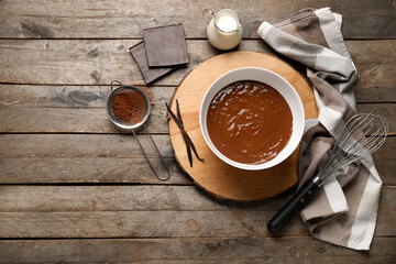 Bowl with hot chocolate, jar of milk and cocoa in sieve on wooden background. Top view