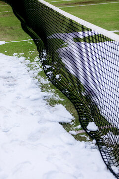 Tennis court with snow-covered grass and net contrasts